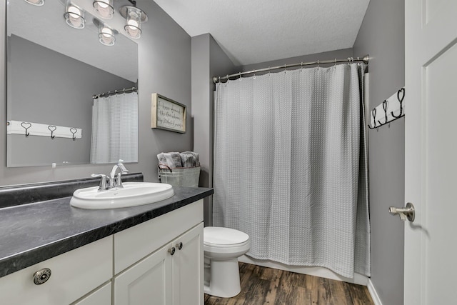 bathroom featuring toilet, a textured ceiling, wood finished floors, and vanity