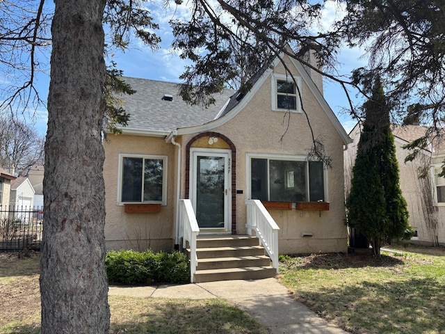 view of front of home featuring fence, a shingled roof, a front lawn, and stucco siding