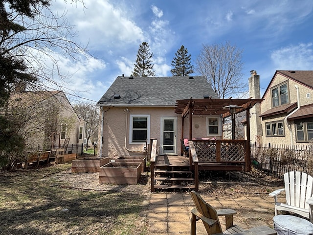 back of property with fence, a pergola, stucco siding, and a garden