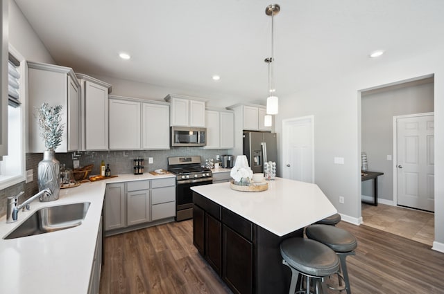 kitchen with appliances with stainless steel finishes, tasteful backsplash, a sink, and a kitchen bar