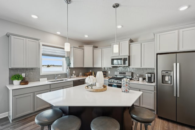 kitchen featuring dark wood-style flooring, stainless steel appliances, a kitchen breakfast bar, and a sink