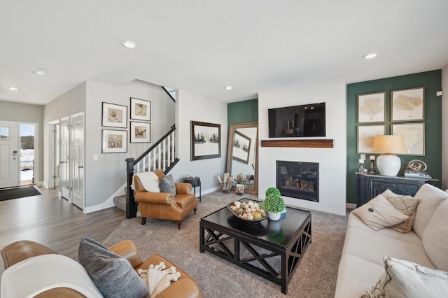 living area with recessed lighting, baseboards, a large fireplace, and stairway