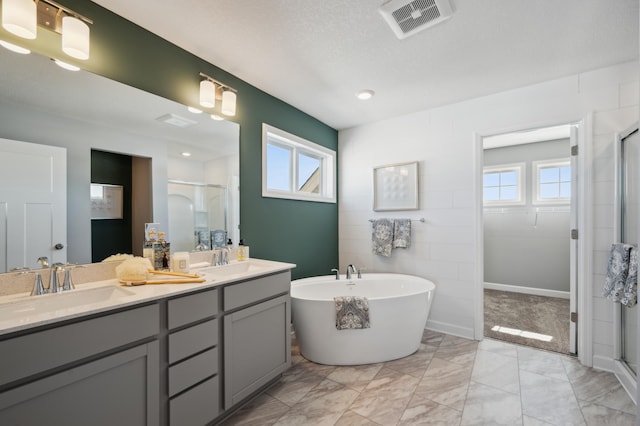 bathroom with double vanity, a freestanding tub, visible vents, and a stall shower