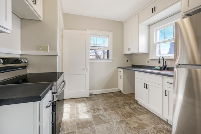 kitchen featuring appliances with stainless steel finishes, dark countertops, a sink, and healthy amount of natural light