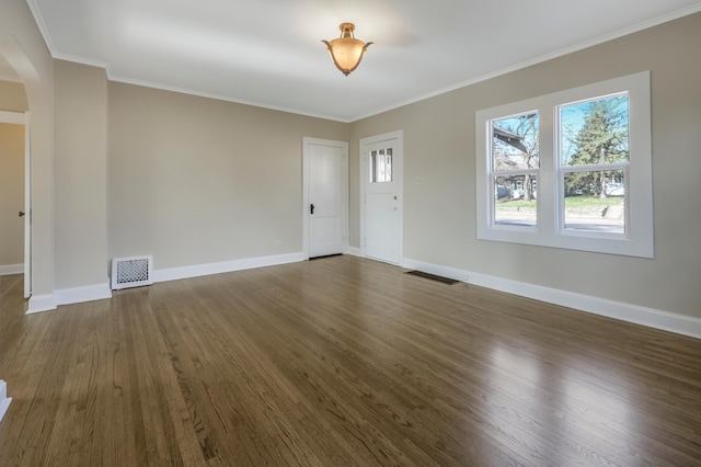 foyer with arched walkways, dark wood-type flooring, crown molding, and baseboards