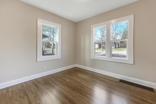 spare room featuring baseboards and dark wood-style flooring