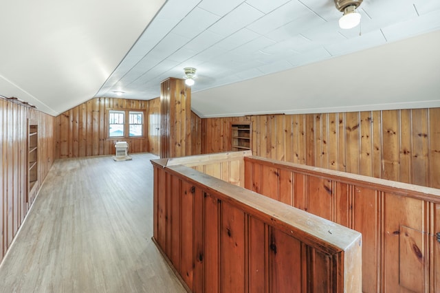 bonus room featuring wood walls, vaulted ceiling, and light wood-type flooring