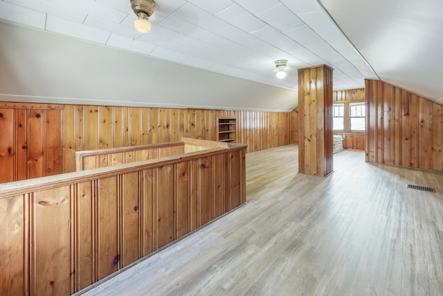 bonus room with wood walls, wood finished floors, and lofted ceiling