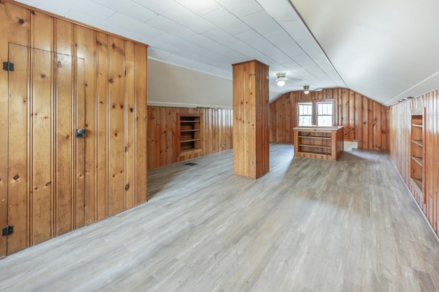 additional living space featuring wood finished floors, wooden walls, and lofted ceiling