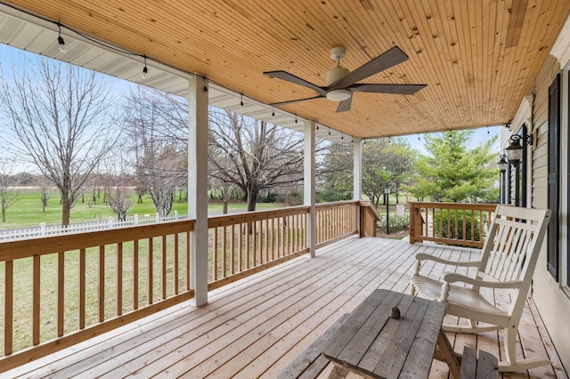 wooden deck with a lawn and a ceiling fan