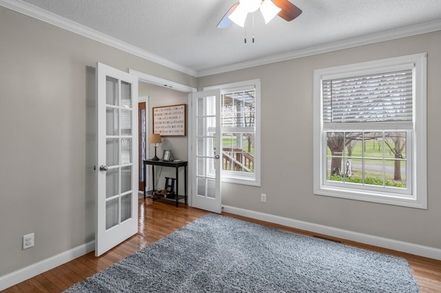 spare room featuring french doors, crown molding, and a healthy amount of sunlight