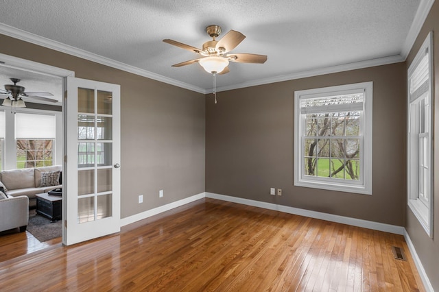 empty room featuring wood-type flooring, a textured ceiling, ceiling fan, and visible vents