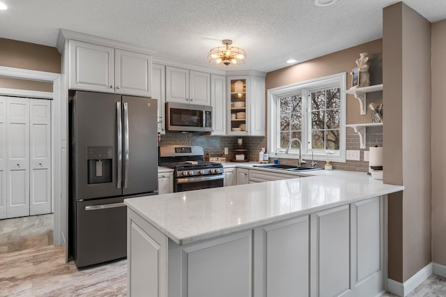 kitchen featuring a sink, white cabinetry, appliances with stainless steel finishes, and a peninsula