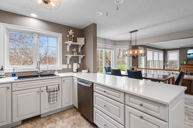 kitchen with open shelves, a notable chandelier, a sink, a peninsula, and stainless steel dishwasher