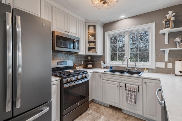 kitchen featuring a sink, a textured ceiling, appliances with stainless steel finishes, and light countertops