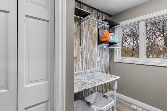 interior space featuring a textured ceiling, visible vents, and baseboards