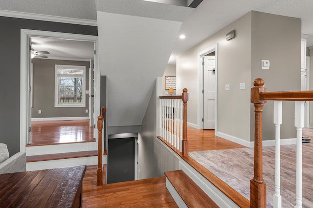 stairway with crown molding, baseboards, ceiling fan, and wood finished floors