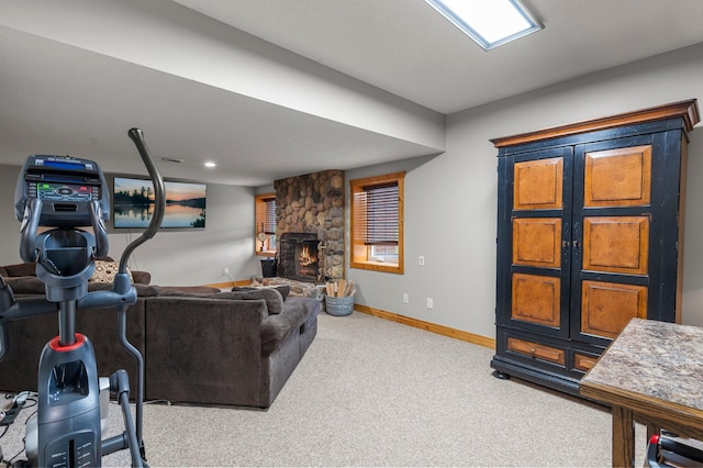 carpeted living room with a stone fireplace and baseboards