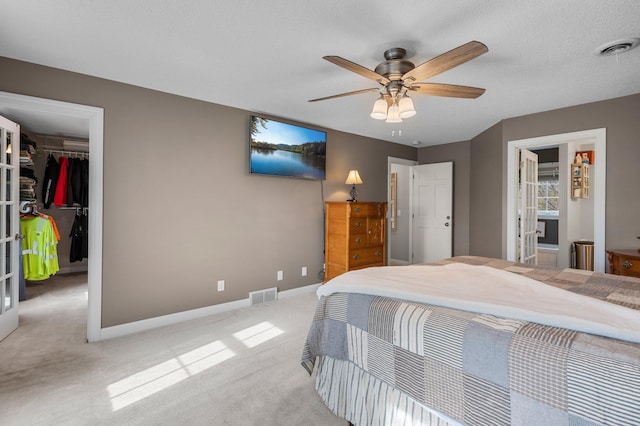 bedroom with visible vents, baseboards, a spacious closet, and light colored carpet