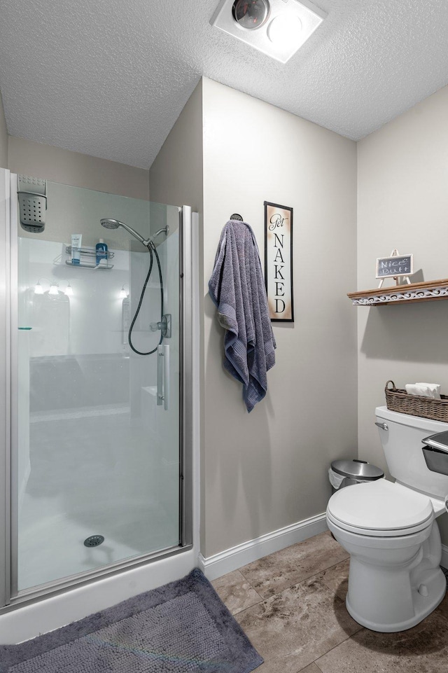 bathroom featuring baseboards, a stall shower, toilet, and a textured ceiling