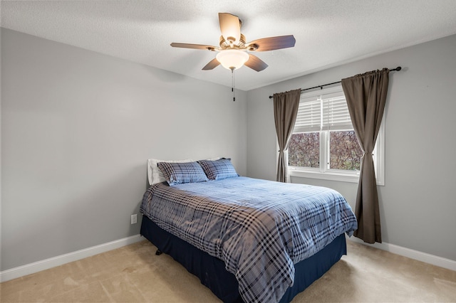 bedroom featuring baseboards, ceiling fan, light carpet, and a textured ceiling