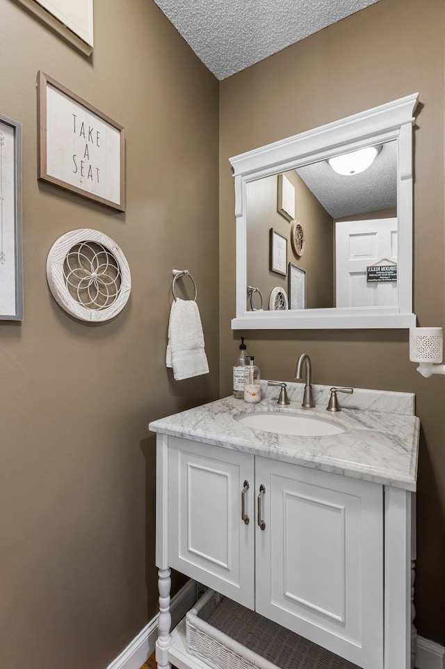 bathroom with vanity, a textured ceiling, and baseboards