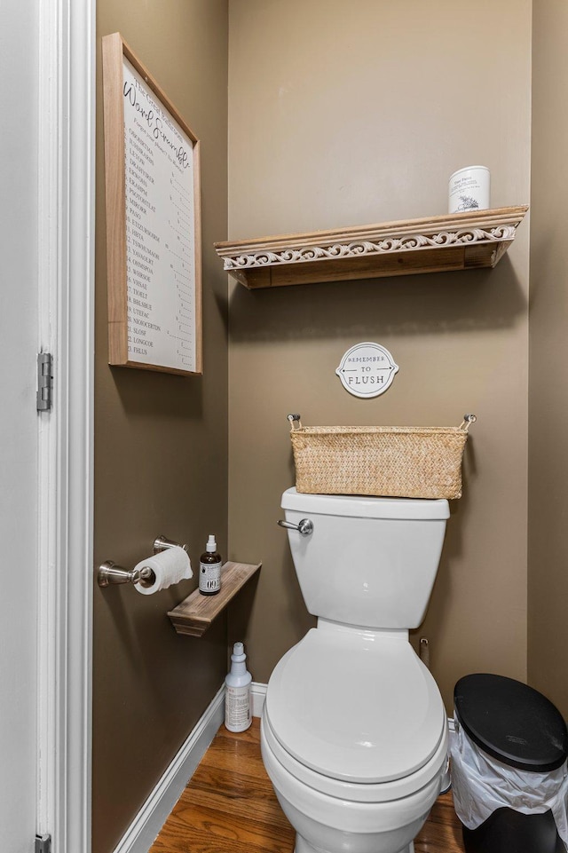 bathroom with toilet, baseboards, and wood finished floors