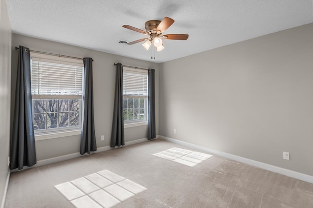 unfurnished room featuring carpet floors, ceiling fan, baseboards, and a textured ceiling