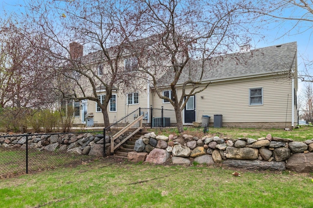 rear view of property with fence, a chimney, a lawn, and roof with shingles