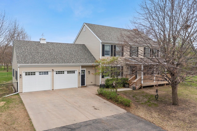 view of front of house with driveway, a chimney, a wooden deck, a garage, and a shingled roof
