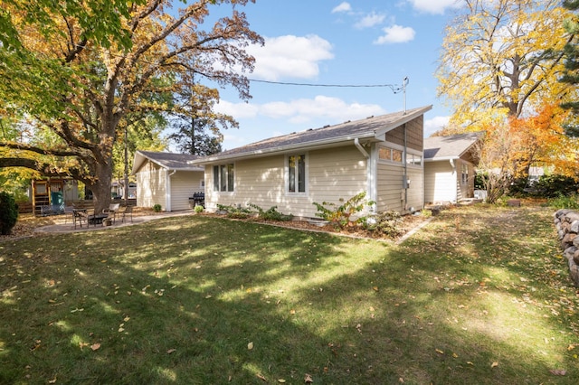 rear view of property with a patio, a yard, and a fire pit