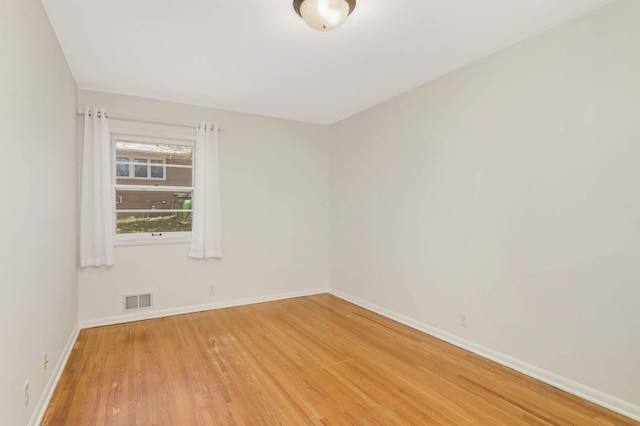 empty room with visible vents, baseboards, and wood finished floors