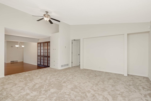 unfurnished room with carpet floors, visible vents, lofted ceiling, and ceiling fan with notable chandelier