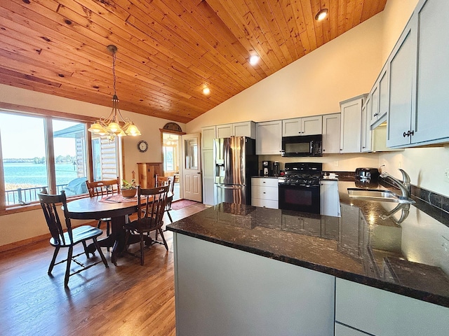 kitchen featuring black appliances, a sink, a peninsula, decorative light fixtures, and wooden ceiling