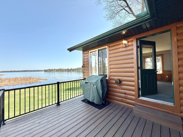 deck with a water view, grilling area, and a lawn