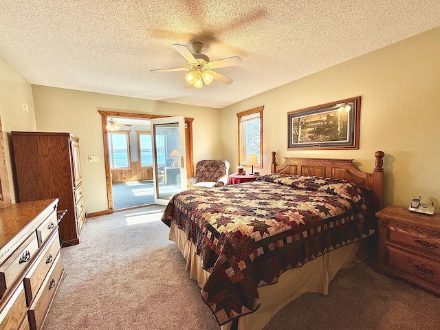 bedroom with access to exterior, light colored carpet, multiple windows, ceiling fan, and a textured ceiling