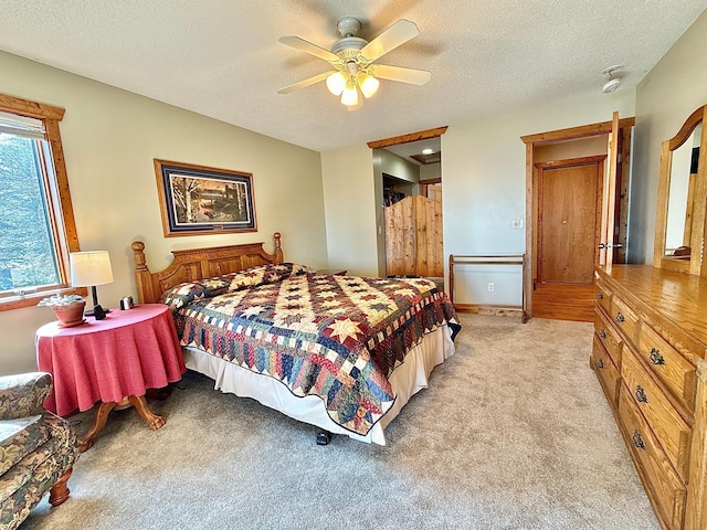 bedroom with light colored carpet, a textured ceiling, and a ceiling fan