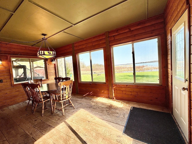 sunroom / solarium featuring a water view and wood walls