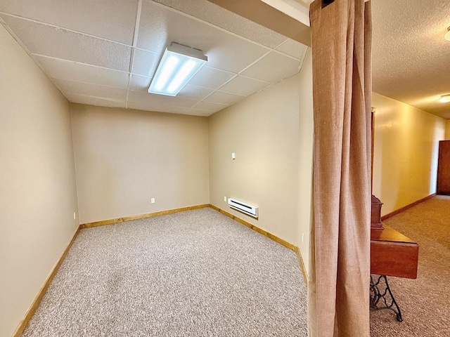basement with carpet floors, a paneled ceiling, baseboards, and a baseboard radiator