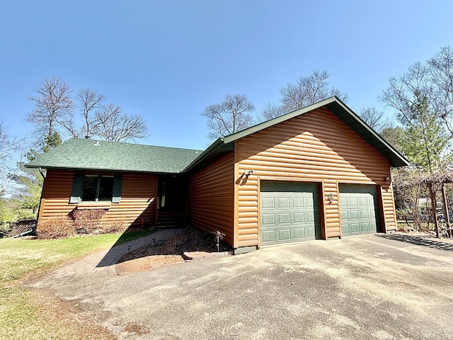 view of front of house featuring log veneer siding, driveway, and a garage