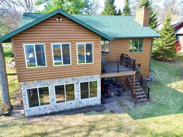 rear view of property featuring a shingled roof, log veneer siding, a chimney, stairway, and a lawn