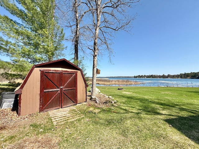 view of green lawn with a shed, a water view, and an outdoor structure