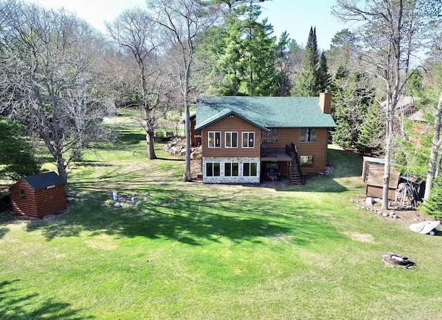 rear view of property featuring a shed, an outdoor structure, a chimney, stairway, and a yard