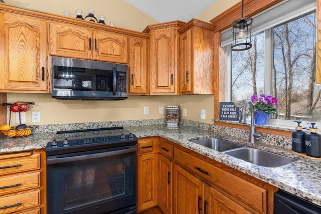 kitchen featuring light stone countertops, a sink, brown cabinetry, decorative light fixtures, and black appliances