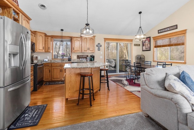 kitchen featuring a breakfast bar, light wood-style flooring, a center island, open floor plan, and black appliances