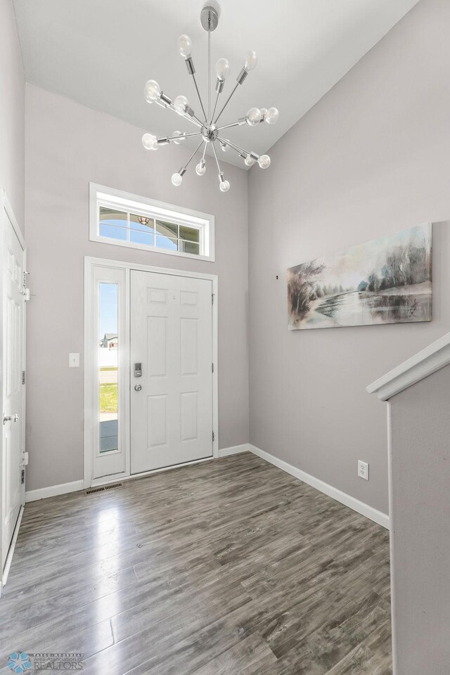 foyer with a chandelier, wood finished floors, baseboards, and a towering ceiling