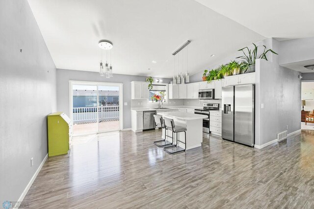 kitchen with stainless steel appliances, light countertops, white cabinets, baseboards, and light wood-style flooring