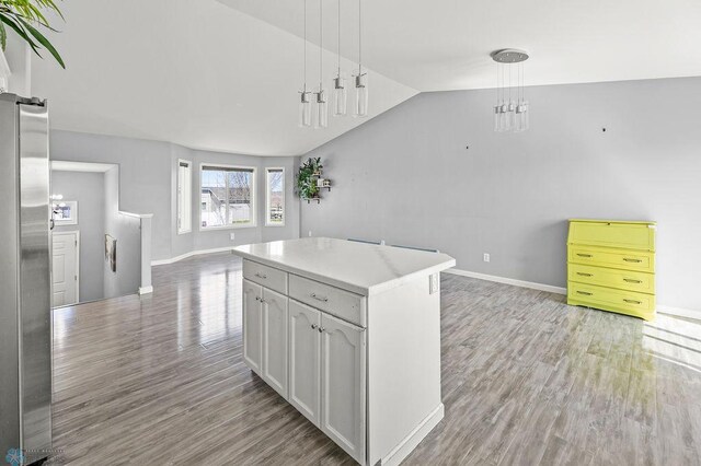kitchen featuring open floor plan, light wood-style floors, lofted ceiling, and baseboards