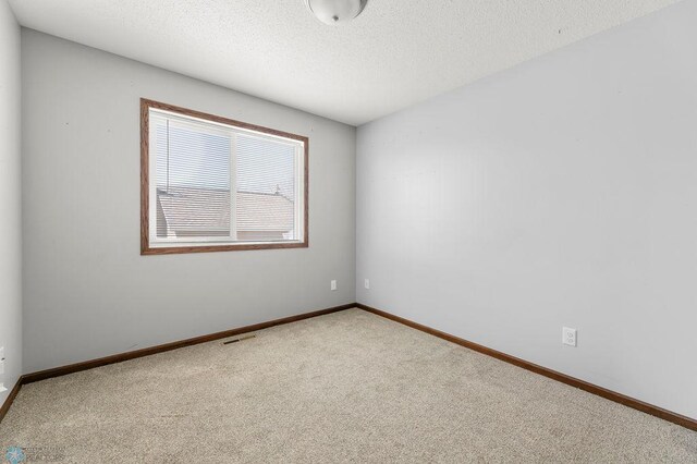 unfurnished room featuring carpet flooring, a textured ceiling, and baseboards