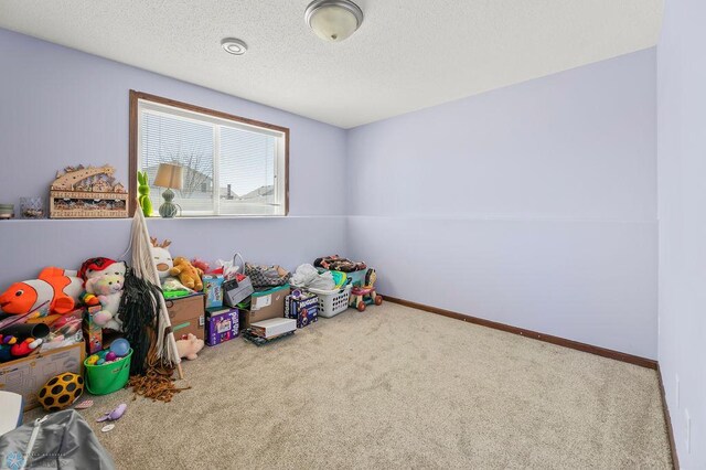 playroom featuring carpet flooring, a textured ceiling, and baseboards